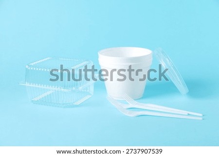 Plastic packaging. Set of disposable tableware on light blue background
