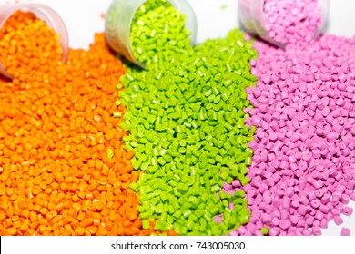 Plastic pellets. Orange green and pink Polypropylene granules scattered on the lab table . Polymeric dye.