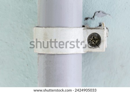 Plastic pipe, as duct for pulling of communication cables fixed to a concrete wall with plastic pipe clamp and screw indoor
