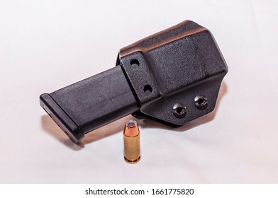 A Plastic Pistol Magazine Holder With A Pistol Magazine In It With A Hollow Point Bullet Next To It On A White Background