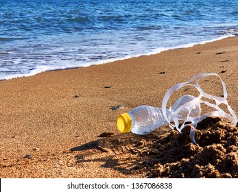 Plastic Pollution. A Plastic Bottle And A Six Pack Plastic Rings On The Beach Shore