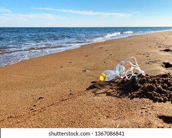 Plastic Pollution. A Plastic Bottle And A Six Pack Plastic Rings On The Beach Shore