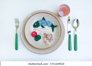 Plastic pollution comes to our tables. Plastic and microplastics pollute the sea and We eat fish wit that have absorbed plastic. Dish with fish and side dishes made of plastic. Isolated on white.