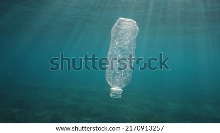Plastic pollution, discarded plastic bottle drifting under surface of the water in sun rays on sunset. plastic bottle in blue water. Plastic garbage environmental pollution problem in Ocean. Baklight