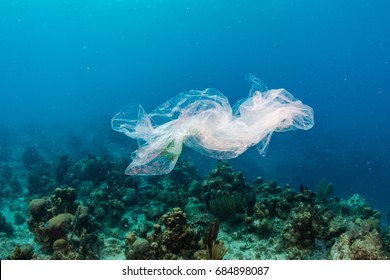 Plastic pollution:- a discarded plastic rubbish bag floats on a tropical coral reef presenting a hazard to marine life