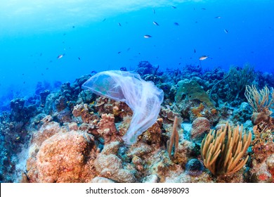Plastic pollution:- a discarded plastic rubbish bags floats on a tropical coral reef presenting a hazard to marine life