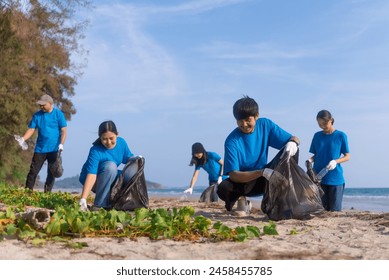 Plastic pollution and environmental problem concept. Happy asian diverse group of volunteers with garbage bags wearing blue t-shirt and cleaning plastic on the beach. Volunteers collecting trash. - Powered by Shutterstock