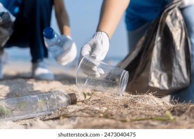 Plastic pollution and environmental problem concept. Close up of female volunteers hands with collecting plastic cup on the beach. Greening the planet. Recycle reduce and reuse concept.