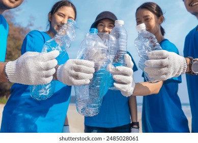 Plastic pollution and environmental problem concept. Happy asian diverse group of volunteers with garbage bags wearing blue t-shirt and cleaning plastic on the beach. Volunteers collecting trash. - Powered by Shutterstock