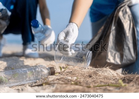 Plastic pollution and environmental problem concept. Close up of female volunteers hands with collecting plastic cup on the beach. Greening the planet. Recycle reduce and reuse concept.