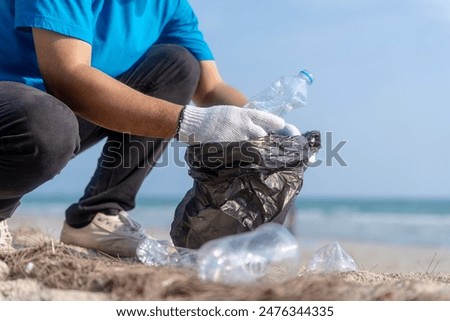 Plastic pollution and environmental problem concept. Close up male volunteer with garbage bags cleaning plastic on the beach. Volunteers collecting plastic bottle in a trash bag. Greening the planet.