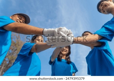 Plastic pollution and environmental problem concept. Happy asian diverse group of volunteers with garbage bags wearing blue t-shirt and cleaning plastic on the beach. Volunteers collecting trash.