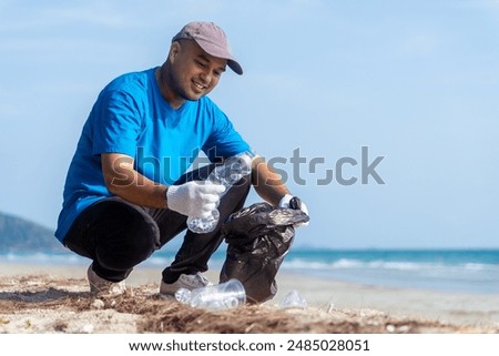 Plastic pollution and environmental problem concept. Happy asian diverse group of volunteers with garbage bags wearing blue t-shirt and cleaning plastic on the beach. Volunteers collecting trash.