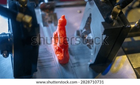 Plastic press machine creating a red orange wolf toy inspired by a howling wolf at Brookfield Zoo in Illinois. A colorful industrial molding process, wildlife attraction, zoo souvenir, and toy manufacturing image.