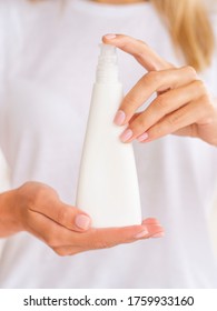 Plastic pump triangular bottle for a gel or mousse. Feminine hands hold White clean jar with space for your logo. Vertical front view cosmetic mockup