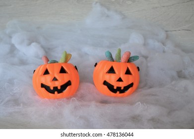 Plastic pumpkin buckets with candy on white spider web background - Powered by Shutterstock