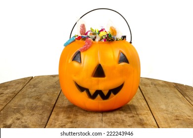 A Plastic Pumpkin Filled With Candy Wooden Table