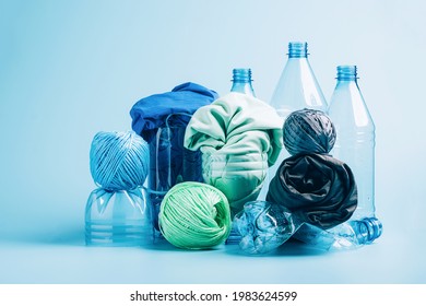 Plastic recycling and reuse concept. Empty plastic bottle and various fabrics made of recycled polyester fiber synthetic fabric on a blue background. Environmental protection waste recycling.