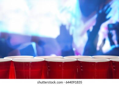 Plastic Red Party Cups In A Row In A Nightclub Full Of People Dancing On The Dance Floor In The Background. Perfect For Marketing And Promotion For Events Or Beer Pong Tournament. College Celebration.