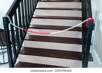 Plastic red   white warning chain links   wooden stair 