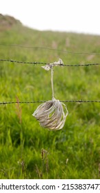 Plastic Rope Hanging To Barb Wire In Green Field