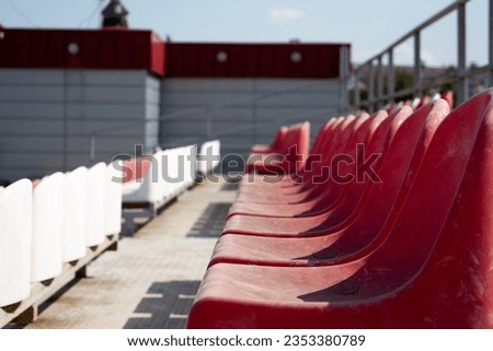 Plastic seats on the grandstand for spectators in the mud. Dirty old red seats in an open-air sports stadium