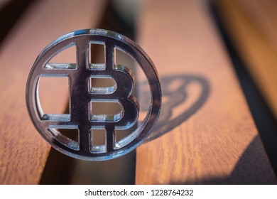 Plastic See Thru Bit Coin On Wooden Background And Lines.