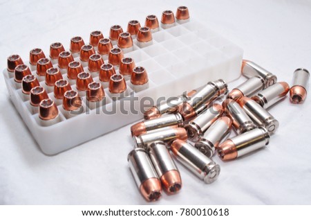 A plastic shell container holding .40 caliber hollow point bullets with a portion of them laying next to it, shot on a white background