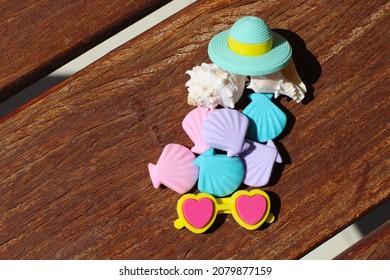 Plastic shells, tiny sunglasses and plastic beach hat on wooden table. Summer concept.