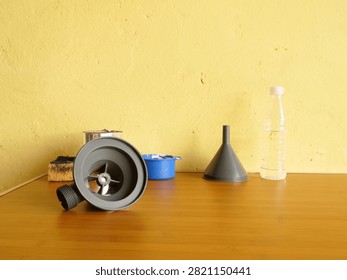 Plastic sink drain trap component resting on a table beside plumbing accessories for wastewater drainage systems.