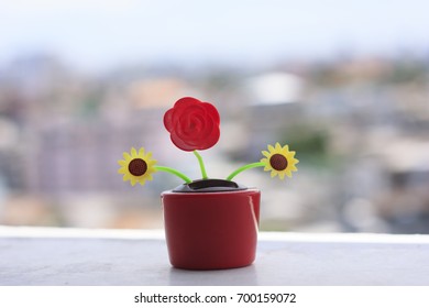 Plastic solar powered dancing flower with the cityscape bokeh background.