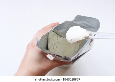 Plastic Spoon With Infant Formula. A Hand Picks Up Infant Formula From A Package.