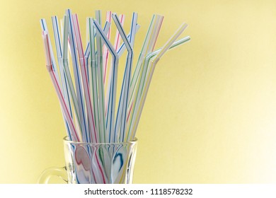 Plastic straws in a glass cup with yellow background
