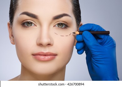 Plastic Surgeon Drawing Dashed Line Under Eye Of Girl. Hand In Blue Glove Holding Pencil. Plastic Surgery, Beauty Portrait, Closeup