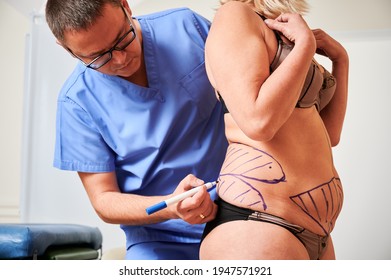 Plastic surgeon marking woman body in clinic.