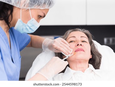 Plastic surgeon preparing for operation on mature woman face - Powered by Shutterstock