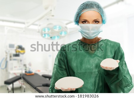 Plastic surgeon woman holding different size silicon breast implants in surgery room interior 
