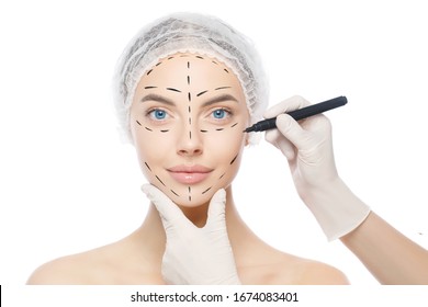 Plastic surgery or face lifting for young woman. Doctor's hands wearing gloves drawing lines, holding head of female patient, isolated on white background