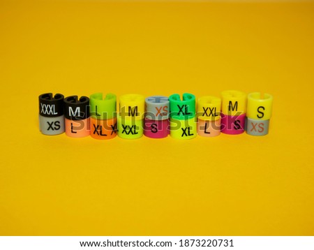 Plastic tags of clothing sizes for the store. Isolated on a yellow background.