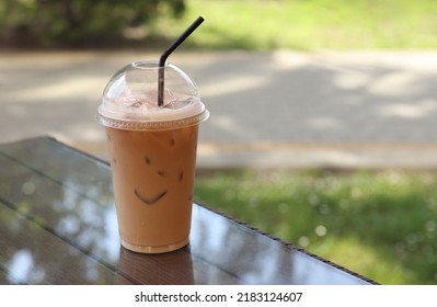 Plastic Takeaway Cup Of Delicious Iced Coffee On Table In Outdoor Cafe, Space For Text