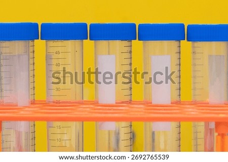 Plastic test tubes empty bottle vials milliliter measurement with caps on yellow background.
