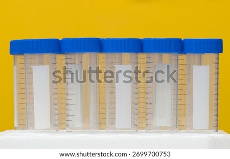 Plastic test tubes empty bottle vials milliliter measurement with caps on yellow background.