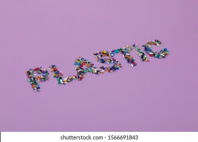 Plastic Text Consisting Of Small Recycled Plastic Pellets Collected From The Sea Water. Rethinking The Environment By Reducing Or Reusing Plastics. Circular Economy Concept. Lilac Purple Background