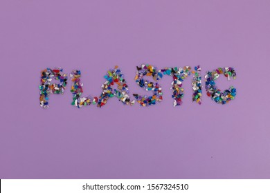 Plastic Text Consisting Of Small Recycled Plastic Pellets Collected From The Sea Water. Rethinking The Environment By Reducing Or Reusing Plastics. Circular Economy Concept. Flatlay, Lilac Purple 