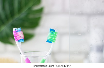 Plastic Toothbrushes On A Blurry Bathroom Background. Freshness, Drops Of Water On The Glass.