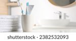 Plastic toothbrushes, toothpaste and towels on white table in bathroom, space for text. Banner design