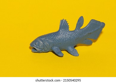 Plastic Toy Coelacanth Fish On A Yellow Construction Paper Background. 