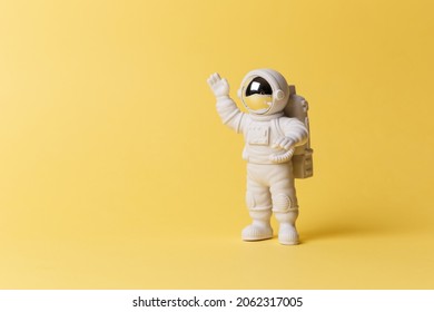 Plastic toy figure astronaut on a yellow background. Copy space. Close-up. The concept of space and space flights. Private space, commercial flights