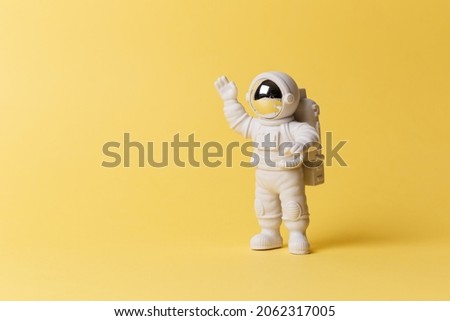 Plastic toy figure astronaut on a yellow background. Copy space. Close-up. The concept of space and space flights. Private space, commercial flights