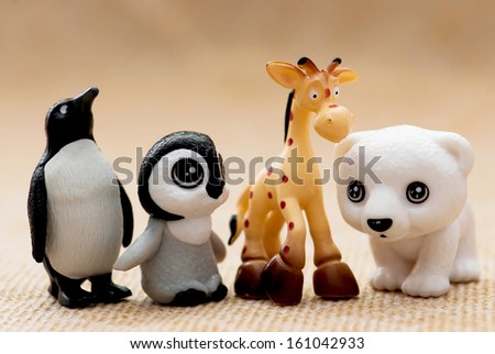 Plastic toy figurines. Penguins, giraffe and white teddy bear.